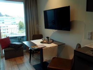 a room with a table and a television on the wall at Lakeside Central Apartment Wörthersee - Free covered Parking, Train & Bus & Supermarket with Supercharger in Sekull