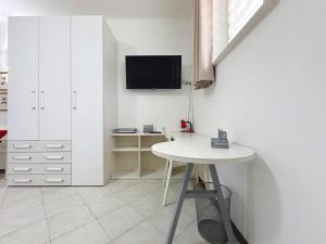 een witte kamer met een tafel en een tv aan de muur bij Alloggio Turistico - I tre Moschettieri - Zona Universitaria e Tribunale Nuovo in Viterbo
