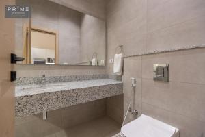 a bathroom with a sink and a toilet and a mirror at Prime Residence Zayed Heights in Sheikh Zayed