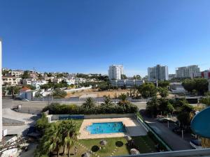 a view of a swimming pool with palm trees and a city at Relaxing Apartment Near the Beach Malabata Tanger in Tangier