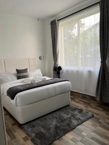 a white bedroom with a bed and a window at Tiny Card Milimani Homes in Kisumu