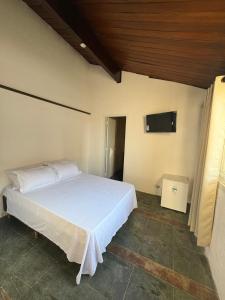 a bedroom with a white bed and a flat screen tv at Pé na areia 5 in Torres