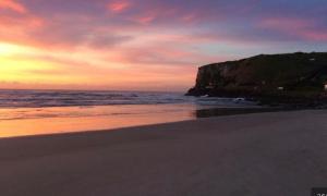 a sunset on a beach with the ocean at Pé na areia 5 in Torres +1 photo