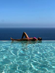 Eine Frau liegt in einem Pool im Wasser in der Unterkunft Le Capase Resort Salento in Santa Cesarea Terme