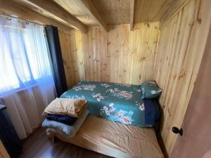 een kleine kamer met een bed in een houten muur bij Cabañas alto de coñaripe in Coñaripe