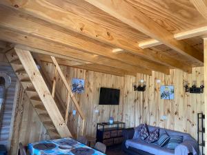 een kamer met een houten plafond, een bank en een tv bij Cabañas alto de coñaripe in Coñaripe