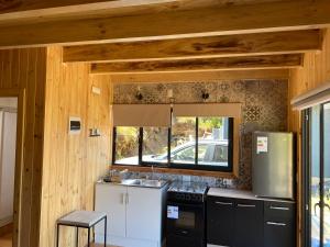 een keuken met een koelkast en een wastafel in de kamer bij Cabañas alto de coñaripe in Coñaripe +15 foto's