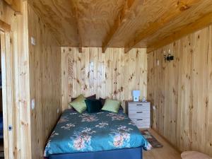 een slaapkamer met een bed en een houten wand bij Cabañas alto de coñaripe in Coñaripe