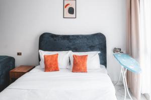 a bedroom with a white bed with orange pillows at Kilimani Chic Studio in Nairobi