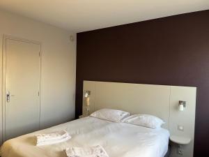 una camera da letto con un grande letto bianco con due cuscini di Brit Hotel L'Arrivée Guingamp a Guingamp