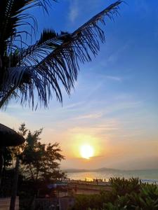 un tramonto sulla spiaggia con una palma di Hoàng Nga 1 Apartment a Ấp Bình Hưng Altre 114 foto