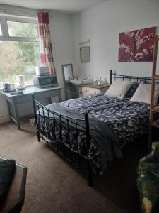 ein Schlafzimmer mit Bett, Schreibtisch und Fenster in der Unterkunft Uplands Room in Sketty