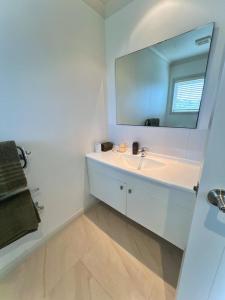a white bathroom with a sink and a mirror at Parkside in Bethlehem in Tauranga
