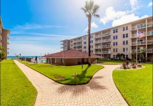 un complexe avec un palmier et un bâtiment dans l'établissement Refreshing oceanfront gem Remarkable sunrises, à New Smyrna Beach