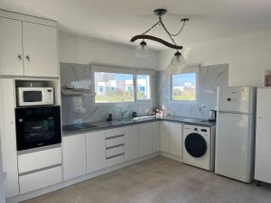 a kitchen with white cabinets and a washer and dryer at Ecos de mar in Mar del Sur