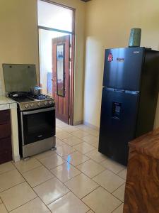 een keuken met een zwarte koelkast en een fornuis bij Casa Ocho in Jacó