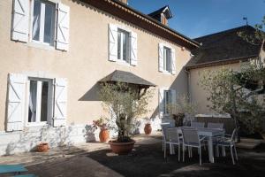 een tafel en stoelen voor een huis bij La Maison du soleil L Aulhere 3 étoiles ,Maison familiale 6-7 personnes, Grand Jacuzzi 6 p in Oloron-Sainte-Marie