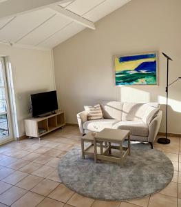 a living room with a couch and a tv at Cozy Beach Home in De Haan