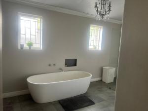 una vasca bianca in un bagno con due finestre di The Townhouse Mkhondo a Piet Retief Altre 17 foto