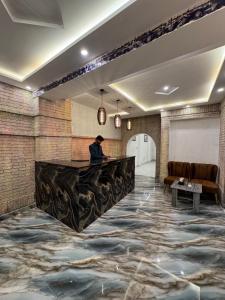 a man sitting at a bar in a room with a tile floor at Gulberg Residency Hotel in Lahore