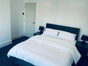 a bedroom with a large white bed with two lamps at Sterling House - by Eazystays in Crewe