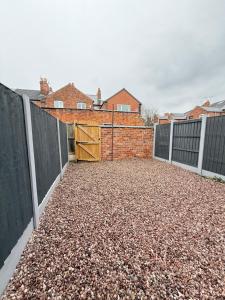 a driveway with a wooden gate and a brick building at Sterling House - by Eazystays in Crewe