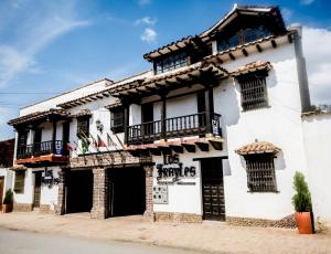 a white building with balconies on a street at Hotel Los Frayles in Villa de Leyva