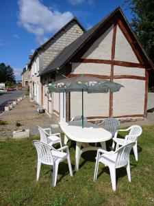 een tafel en stoelen met een parasol voor een gebouw bij Les 4 Portes in Le Mesnillard