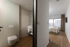 a bathroom with a toilet and a sink and a bed at Sunday Residence Split in Split +44 photos