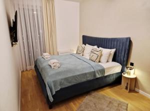 een kleine slaapkamer met een bed met een blauw hoofdeinde bij Infinity Apartment & Privat Garage in Sarajevo