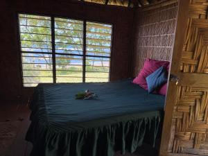a bedroom with a bed with a blue comforter and two windows at Fireworks bungalows in White Sands