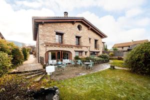 una vista esterna di una casa in mattoni con tavoli e sedie di Hotel Boutique Barosse Family & Pet Friendly Roo a Jaca