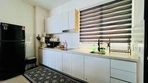 a kitchen with white cabinets and a black refrigerator at Mutiara Melaka Beach Resort Condominium,Pantai Puteri Melaka in Malacca