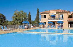 a swimming pool with chairs and umbrellas next to a building at Résidence Odalys Les Océanides in La Londe-les-Maures