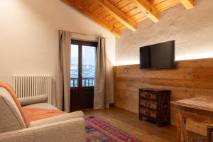 een woonkamer met een televisie aan de muur bij Maisons Grandes Murailles in Valtournenche