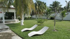 two white chairs on the grass near a house at Alojamiento con alberca privada y jardín grande in Tecolutla