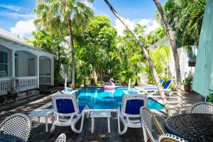 una piscina con sedie, un tavolo e un galleggiante rosa di Papa's Hideaway a Key West