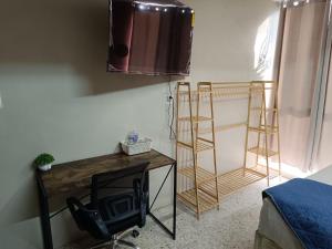 een kamer met een tv en een bureau met een stoel bij Habitación 102 Cordoba Centro Estacionamiento in Córdoba
