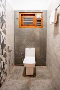 a bathroom with a toilet and a window at Aura Heaven in Thanjāvūr