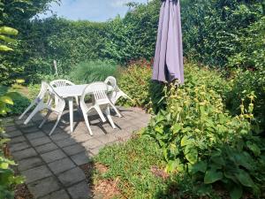 een tafel en stoelen en een parasol op een patio bij Logerenbijonsz in Berghem
