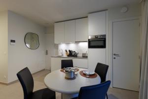 a kitchen with a table and chairs and a kitchen with white cabinets at X-Corner Ostend - Casselbergh Residences in Ostend