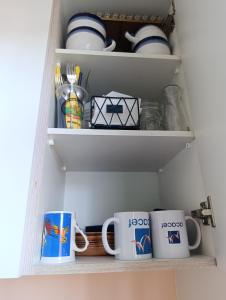 een kast vol kopjes en mokken in een keuken bij Condomínio Sol de Verao in Florianópolis