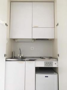 una cucina bianca con mobili bianchi e un lavello di Zurich HB Station Studio, Leon a Zurigo