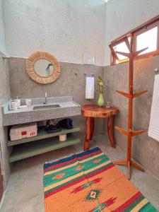 ein Badezimmer mit Waschbecken, Spiegel und Tisch in der Unterkunft Zami 03 & 04 in Pôrto de Pedras