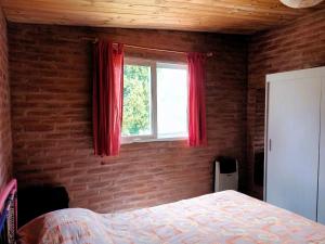 a bedroom with a bed and a window with red curtains at Cabañas Las Pasionarias in Tanti