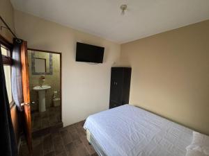 a bedroom with a bed and a tv on the wall at Hotel El Alero in Chimaltenango