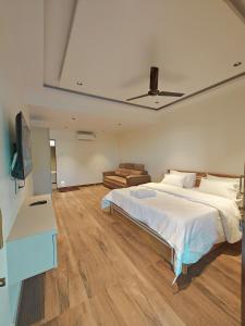 een slaapkamer met een groot wit bed en een bank bij D-LITE COTTAGE in Mahabaleshwar