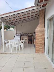 een patio met witte tafels en stoelen en een bakstenen gebouw bij Casa com 3 Quartos Enseada Encantada in Porto Belo