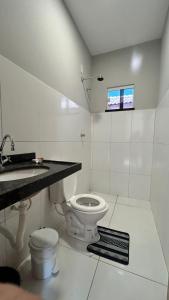 a white bathroom with a toilet and a sink at Casa de praia Cleo in Luis Correia