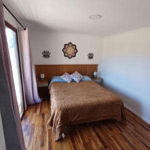 een slaapkamer met een bed en een houten vloer bij Tiny Tunquen in Valparaíso